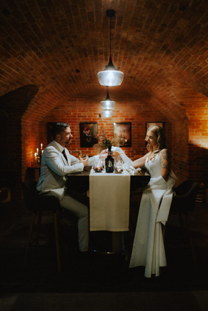 Ein förmlich gekleidetes Paar speist bei Kerzenlicht in einem gemütlichen Restaurant mit Backsteinmauern - eine ideale Hochzeitslocation in Österreich für einen unvergesslichen romantischen Abend.