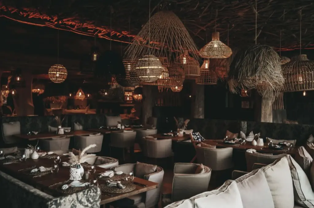 Gemütliches Restaurant mit warmer Beleuchtung, Korblampen, gepolsterten Stühlen und gedeckten Tischen in rustikaler, einladender Atmosphäre - perfekt als Ihre Hochzeitslocation in Österreich.